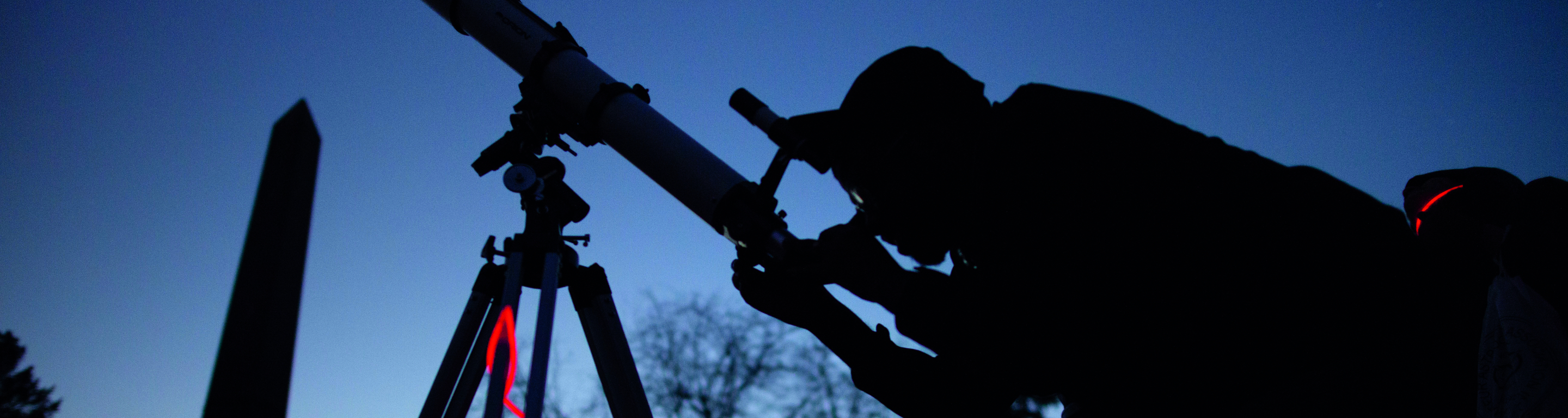 Student looks through a telescope at dawn
