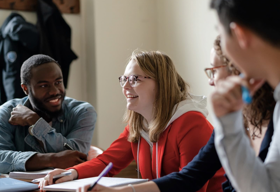 students at a table in classroom holding a discussion
