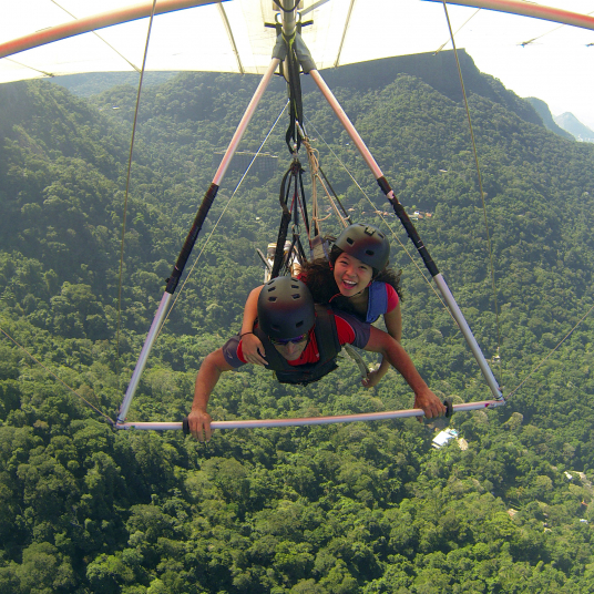 A student and a guide hang glide over the mountains of Rio de Janeiro