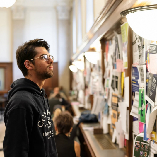 a student staring at a bulletin board covered in flyers