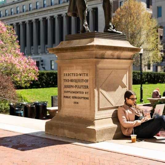 Pulitzer statue with a student studying on steps