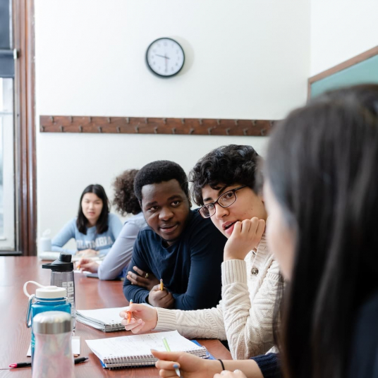 students interacting while sitting at a table in a classroom