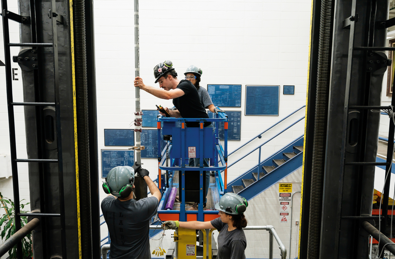 Students work on a metal construction site in a forklift.
