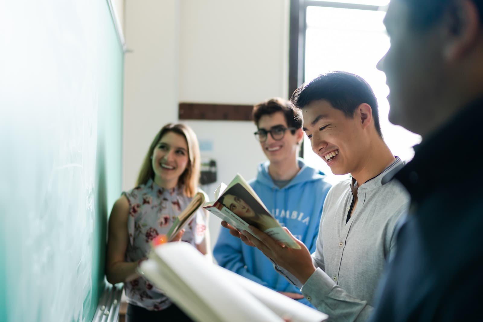 Four Columbia students refer to texts while working at a chalkboard