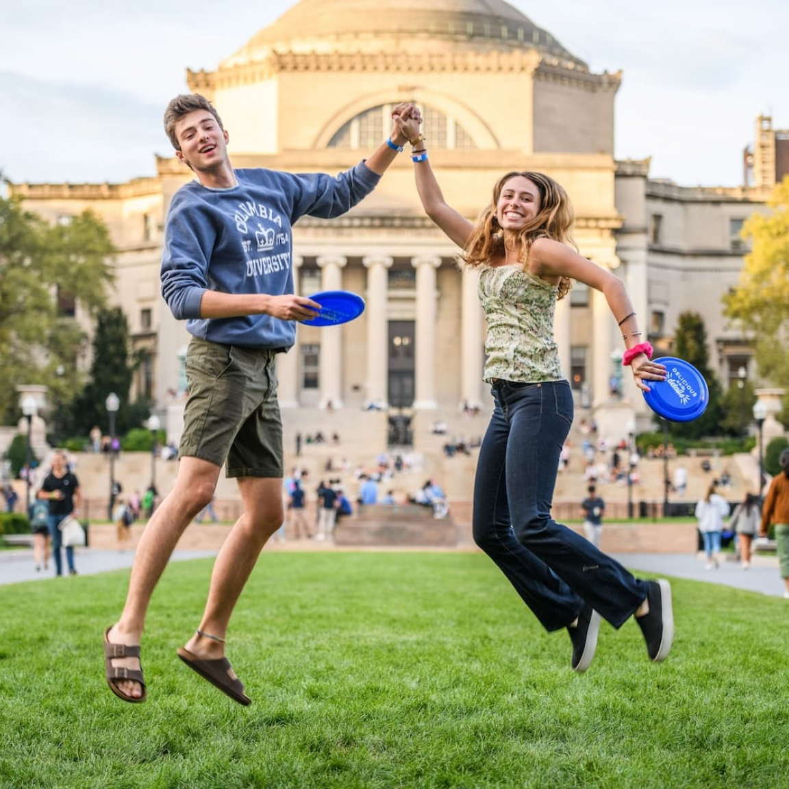 Students hold hands and frisbees on South Lawn in front of Low Library