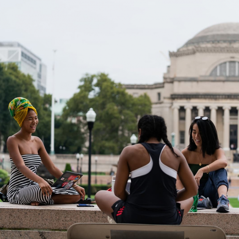 students sitting on campus with Low library in background