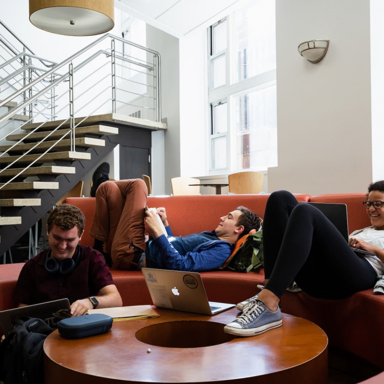 Students sitting on the couches in a lounge looking at laptops