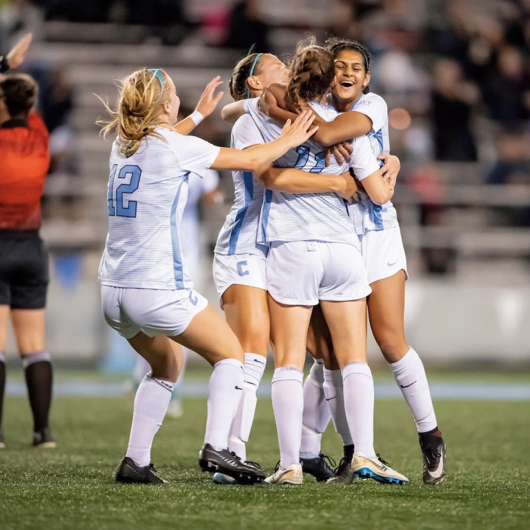 Women's soccer team hugging on the field