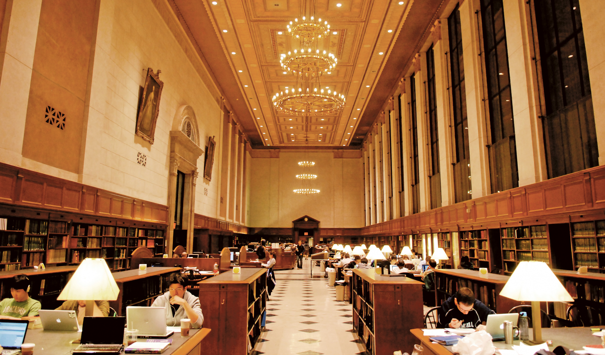 Students study in the library. Chandeliers are pictured above.