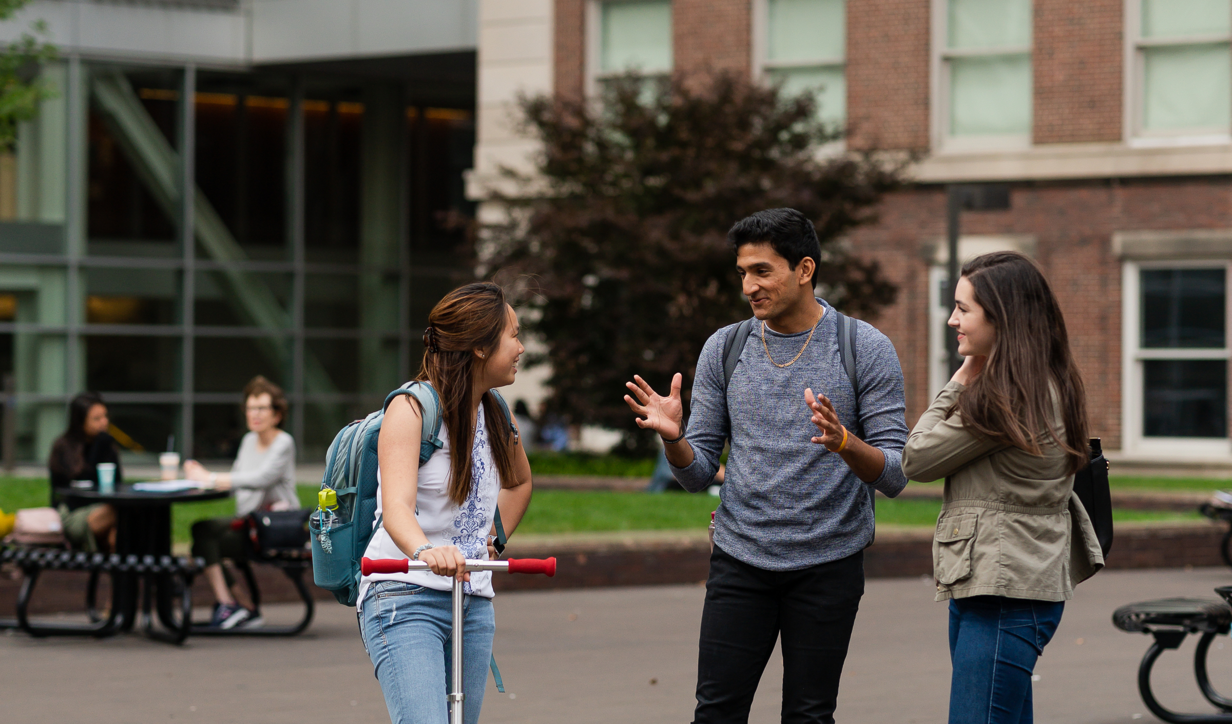 Three students stand together on campus and chat