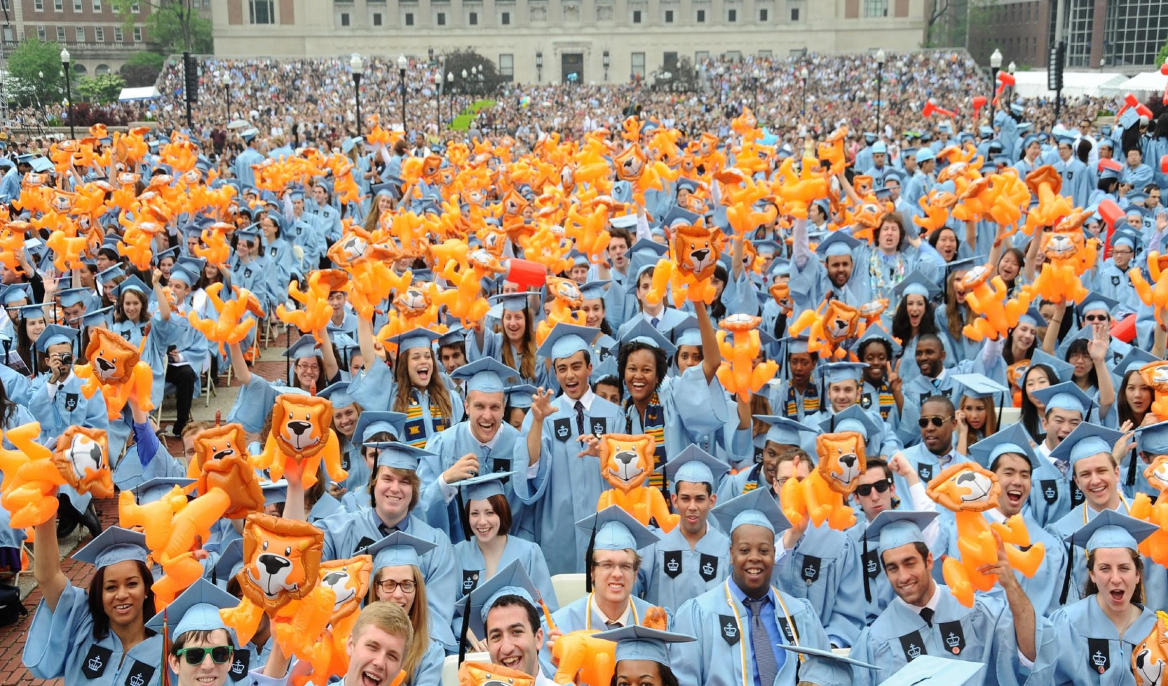 A sea of Columbia students in blue robes with inflatable lions during Commencement
