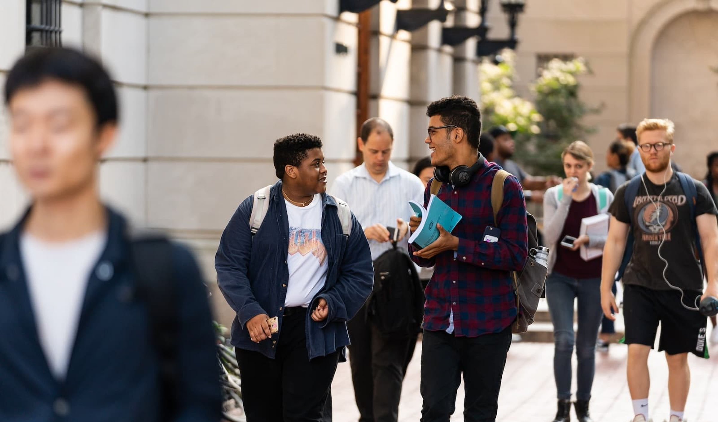 Two students walking behind Hamilton Hall