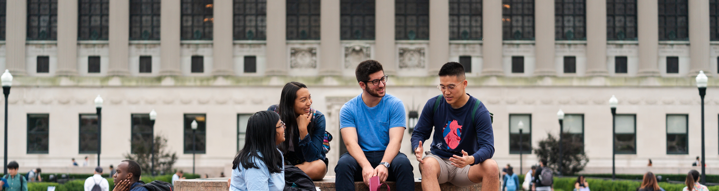 Four students sit at the Sundial on Columbia's campus