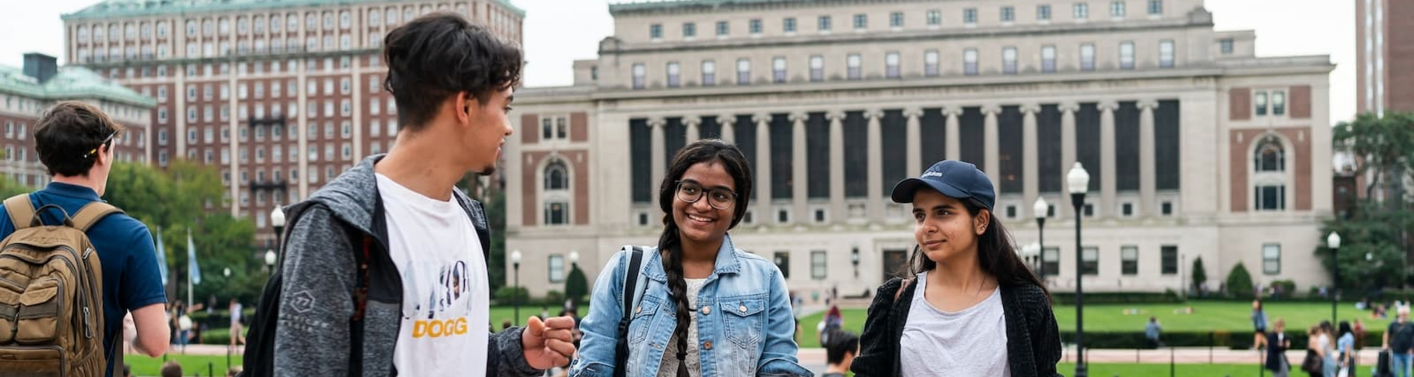 Three students walk across Low Plaza in conversation