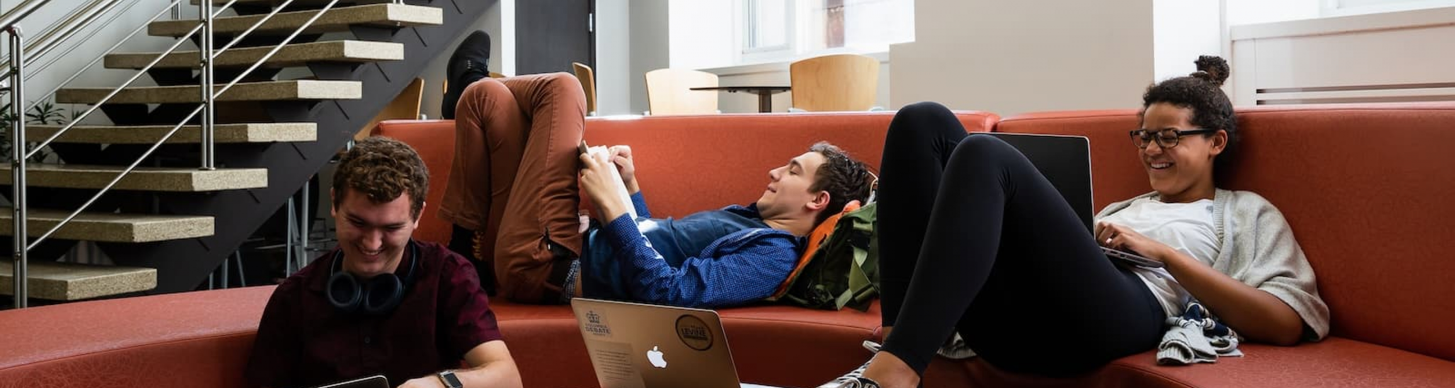 Students sitting on the couches in a lounge looking at laptops