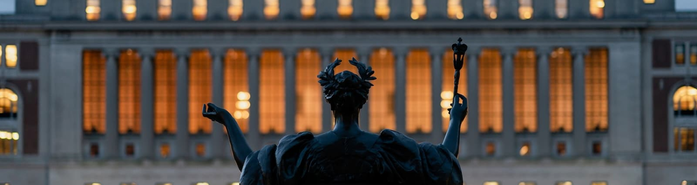 View of Butler Library at dusk from behind Alma Mater