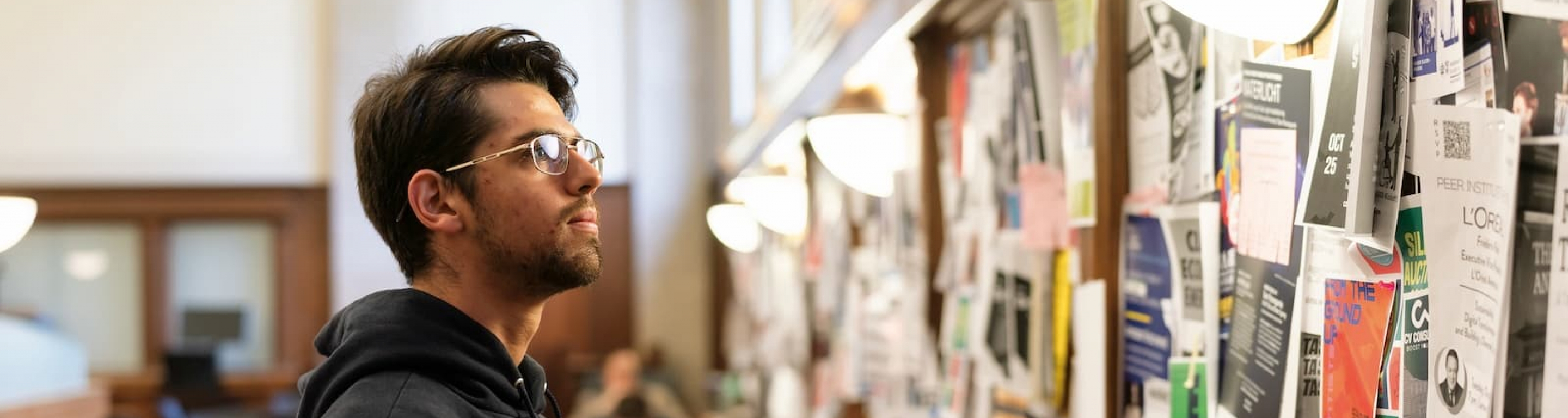 a student staring at a bulletin board covered in flyers
