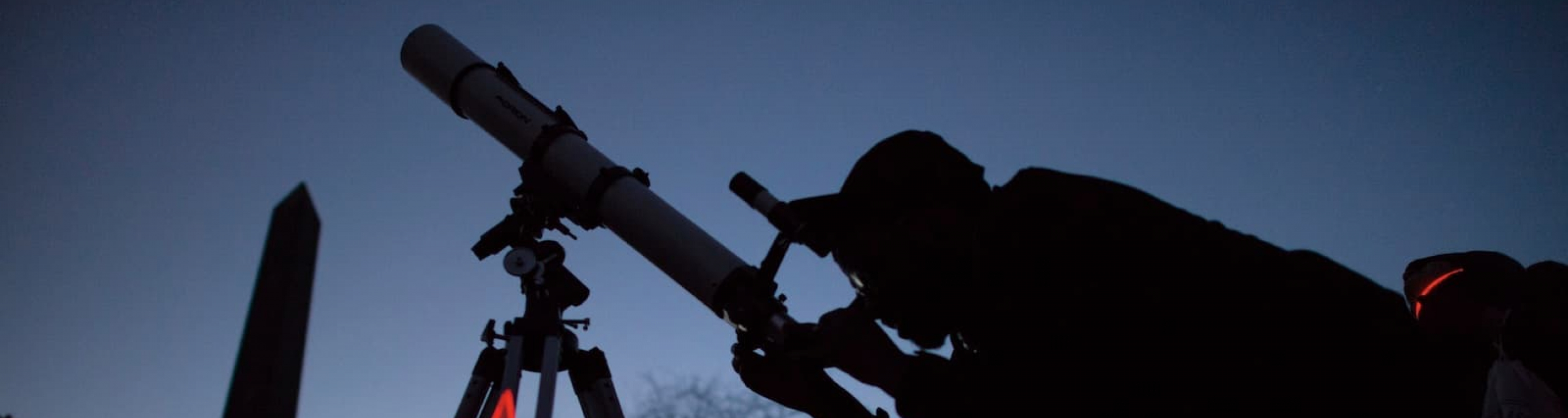 Student looks through a telescope at dawn