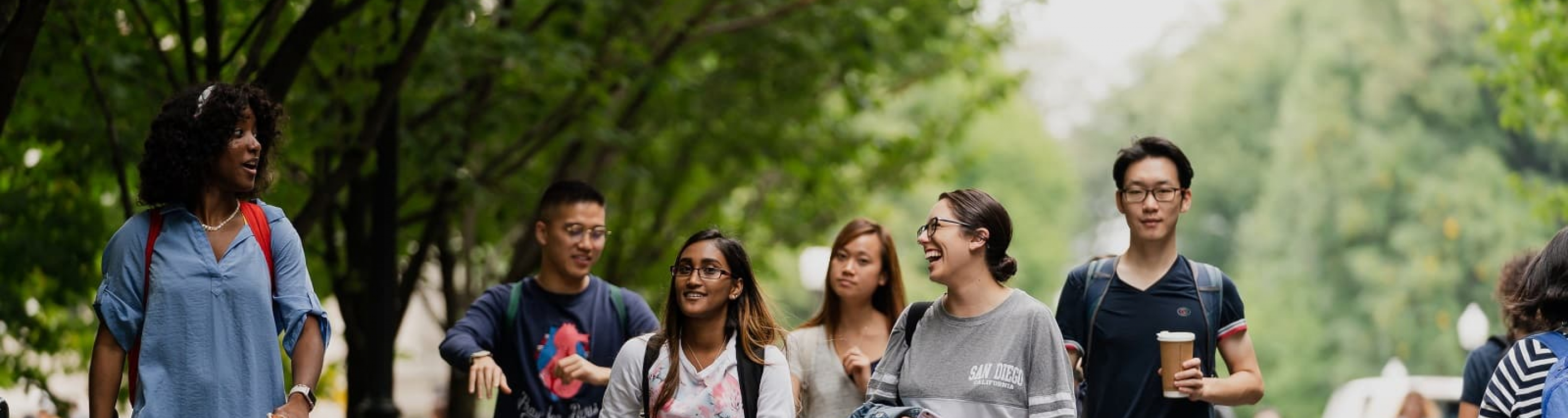 Five students walking down College Walk in spring