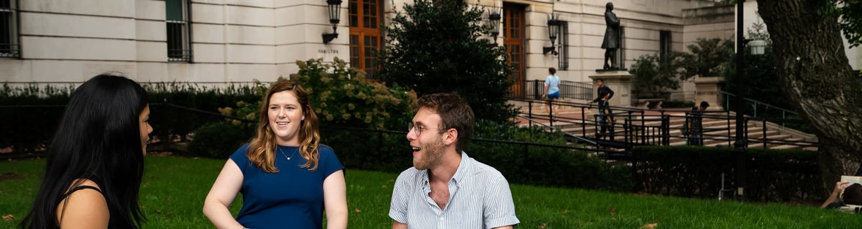 Three students study on the lawn