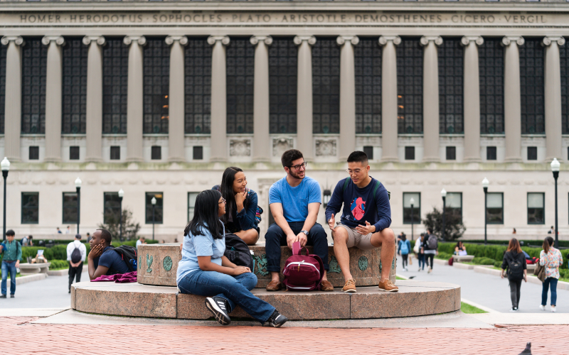 Four students sit at the Sundial on Columbia's campus