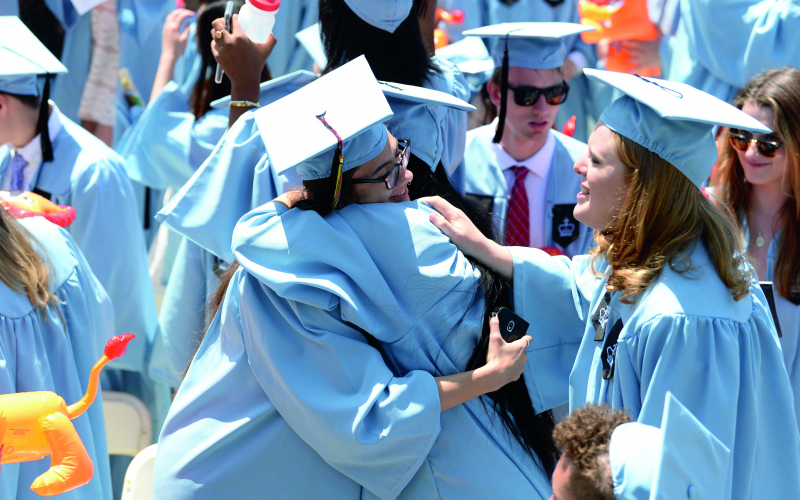 Students in Columbia Blue graduation robes embrace at Commencement