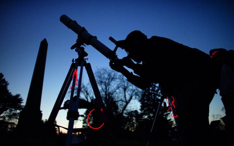 Student looks through a telescope at dawn