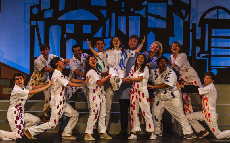 Students in white jumpsuits at the conclusion of the Varsity Show
