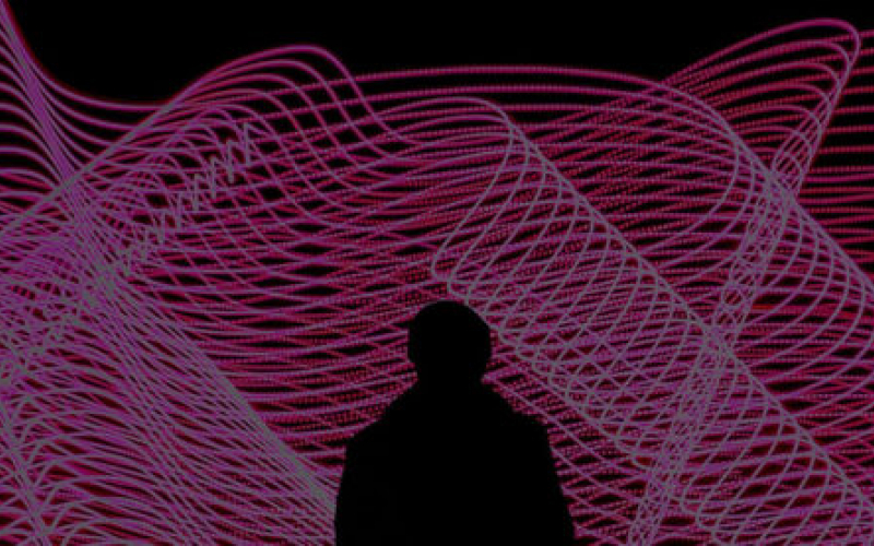 A silhouette stands in front of a data visualization