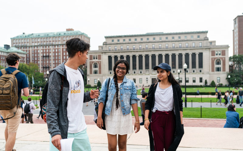 Three students walk across Low Plaza in conversation