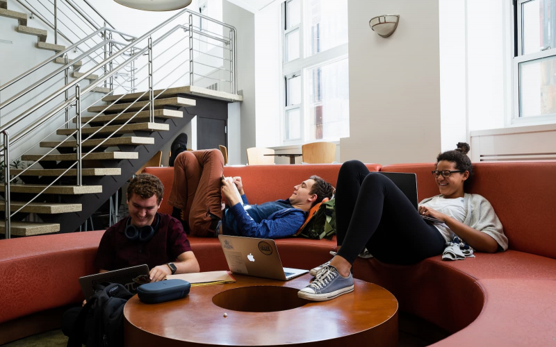 Students sitting on the couches in a lounge looking at laptops