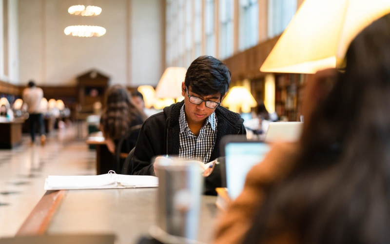 A student reads at a table at Butler Library