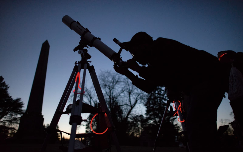 Student looks through a telescope at dawn
