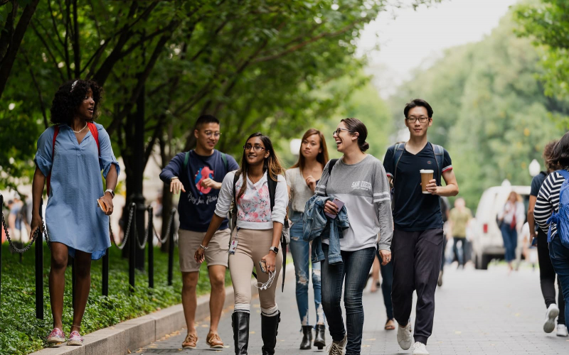 Five students walking down College Walk in spring