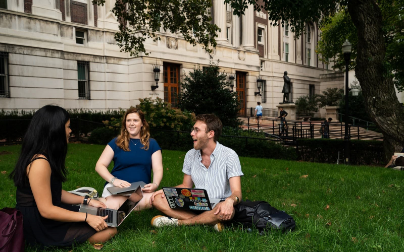 Three students study on the lawn