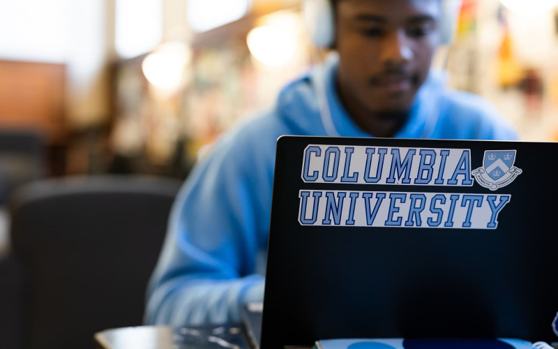 Student working at laptop with Columbia sticker
