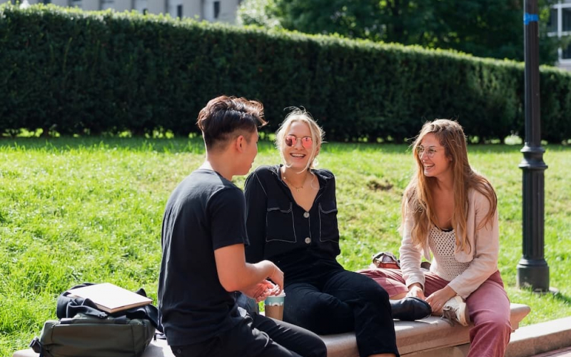 three students sitting on a bench with Butler Library in the background
