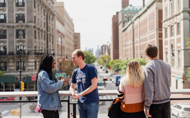 Four students stand on Law Bridge overlooking Amsterdam Avenue facing South